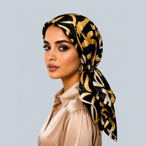 Model wearing the Gilded Interlocking Crescents satin turban, featuring bold metallic gold geometric shapes on a black background