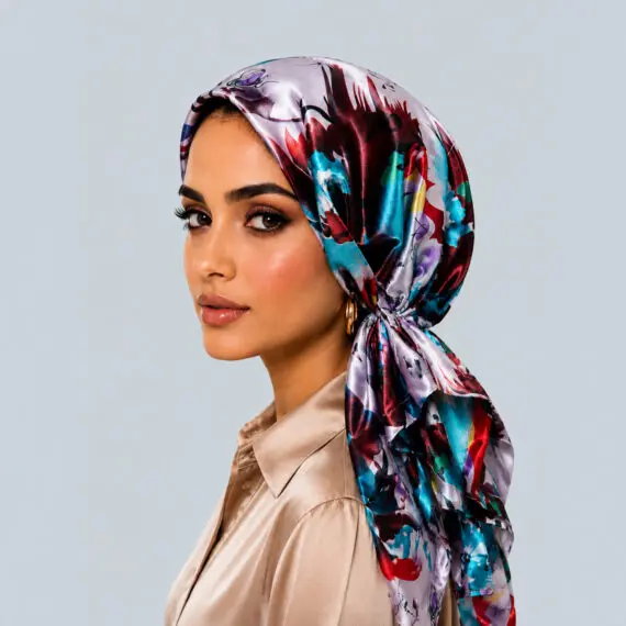 Model wearing the Painterly Jewel Bloom watercolor silk turban showcasing deep burgundy and turquoise splashes on silver-grey